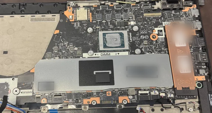 A laptop opened on a workbench with the back cover removed, showing the mainboard, processor, memory shield and storage bay before a repair is quoted.